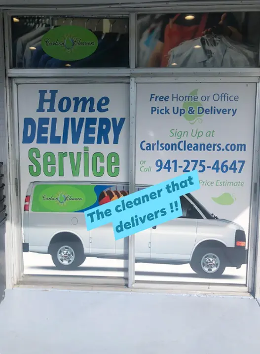 Window advertisement for Carlson Cleaners showing a van and promoting home or office pick-up and delivery service, with contact information and the slogan "The cleaner that delivers!!.